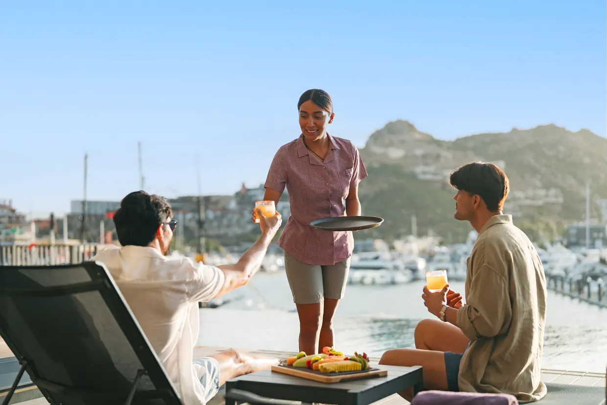 Guests enjoying poolside drink service overlooking the marina at Breathless Cabo San Lucas.