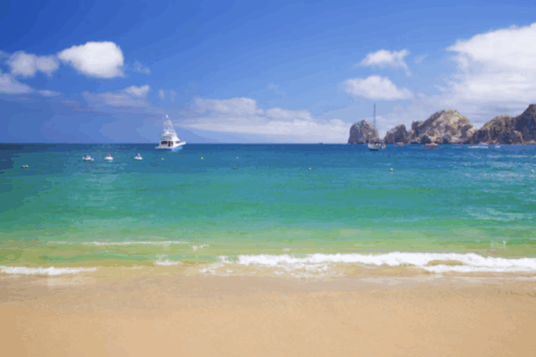 Scenic view of Cabo San Lucas Bay with turquoise water, golden sand, and Land’s End rock formations in the distance.