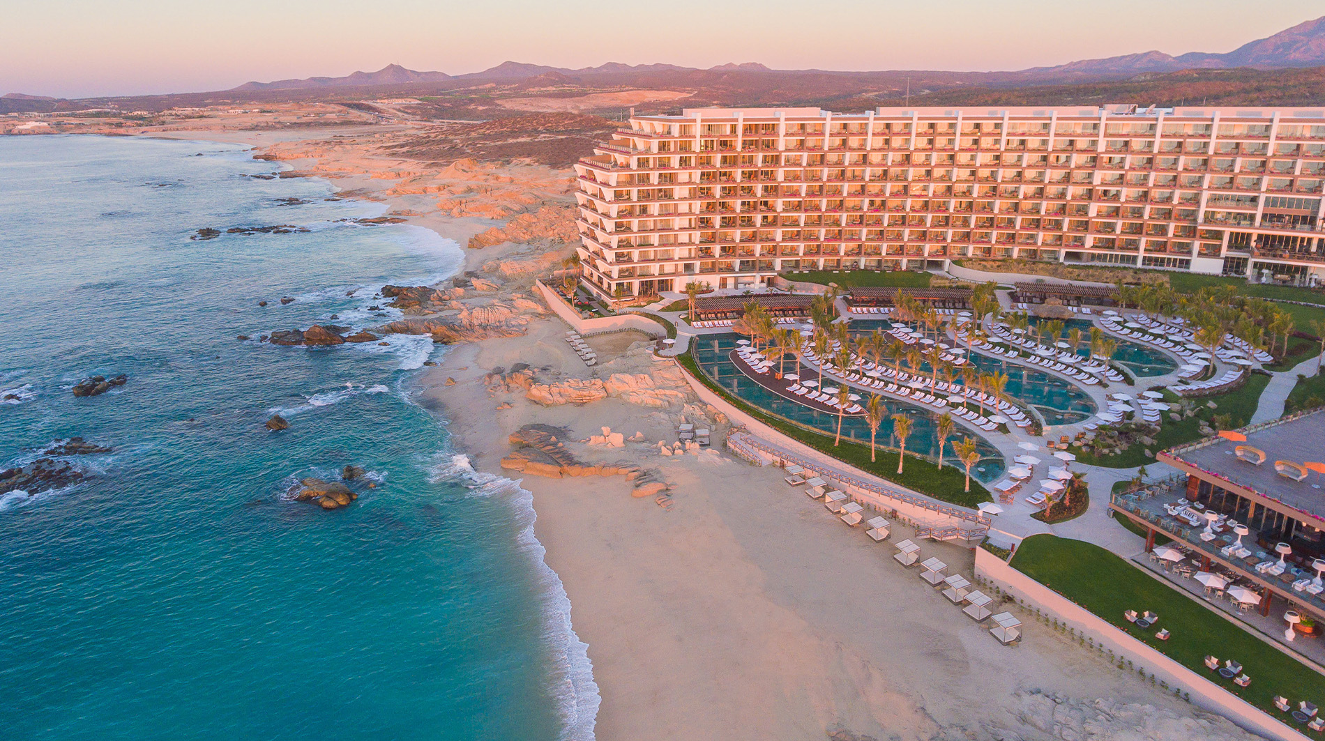 Aerial view of Grand Velas Los Cabos showcasing oceanfront infinity pools and luxury terrace suites.