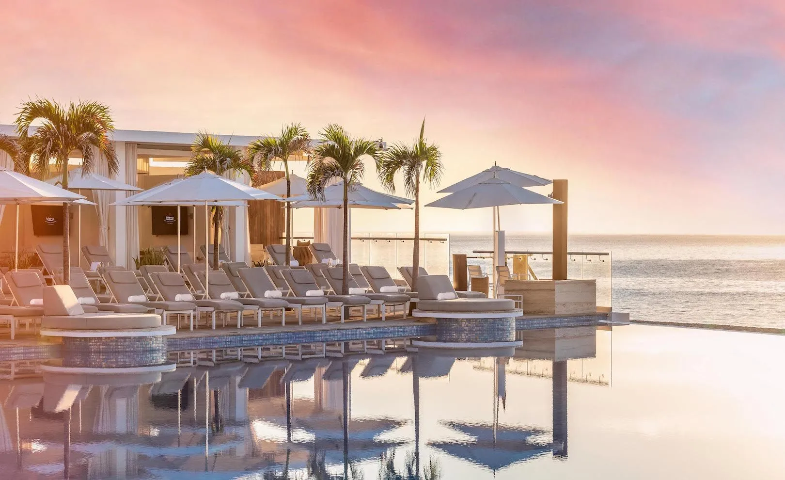 Le Blanc Spa Resort Los Cabos infinity pool and oceanfront cabanas at sunset.