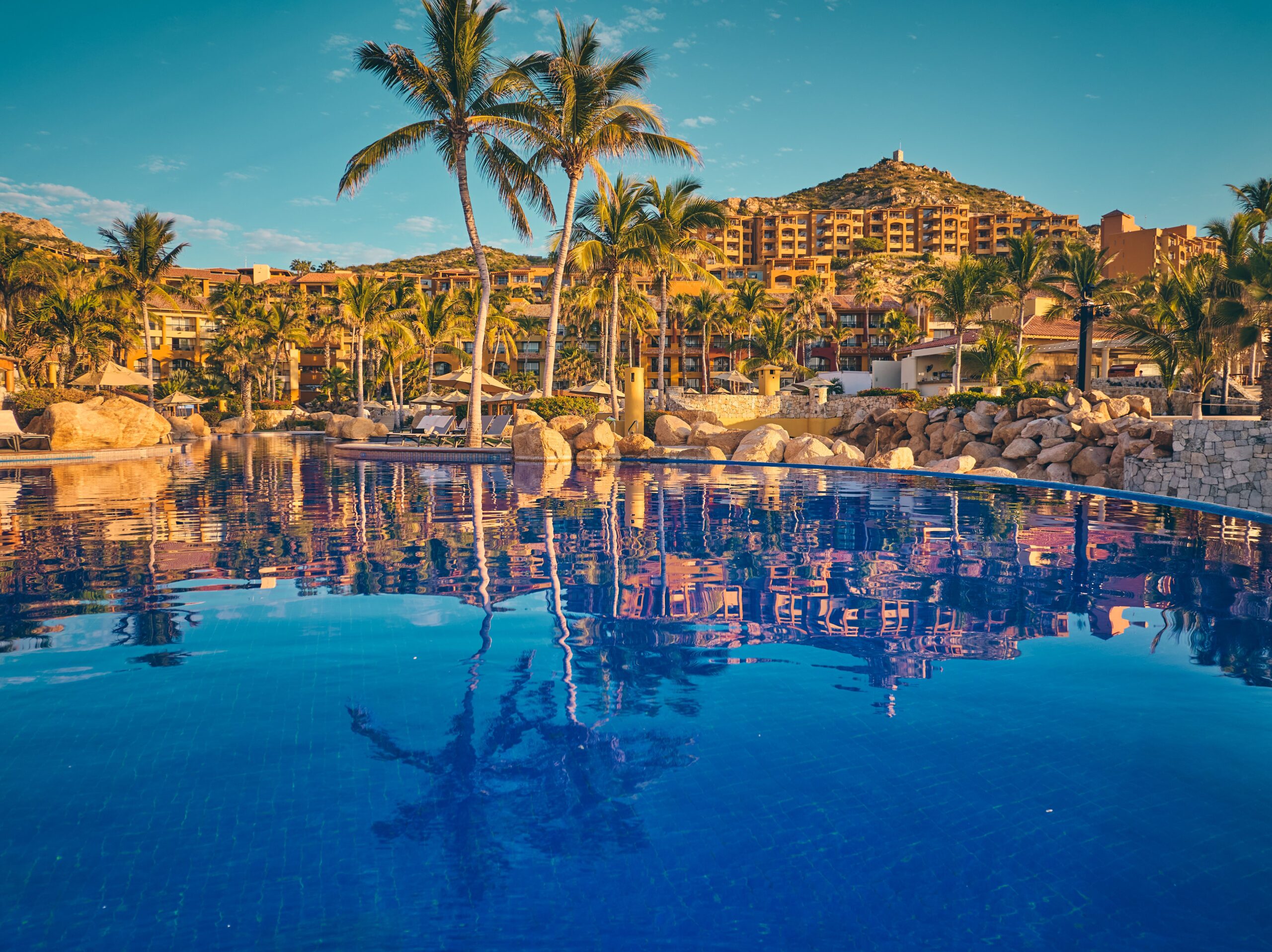 Pueblo Bonito Sunset Beach resort pool reflecting hillside suites at sunset.
